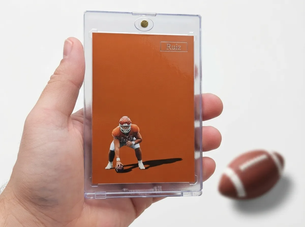 Hand holding magnetic case with orange minimalist fantasy football trophy card on white tabletop.