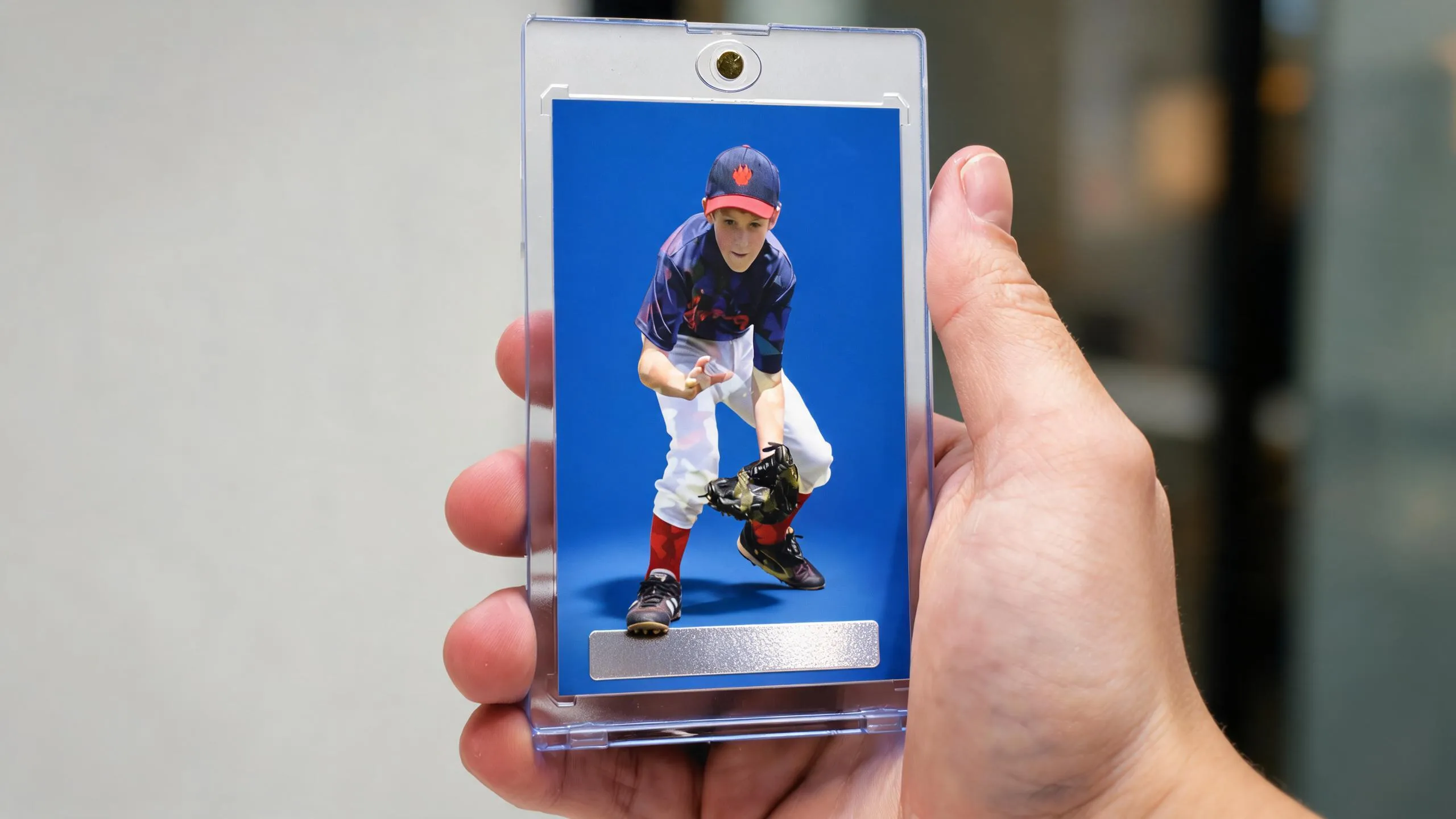 Hand holding magnetic card case, blue athlete card, showcasing high school sports fundraising ideas keepsake design.