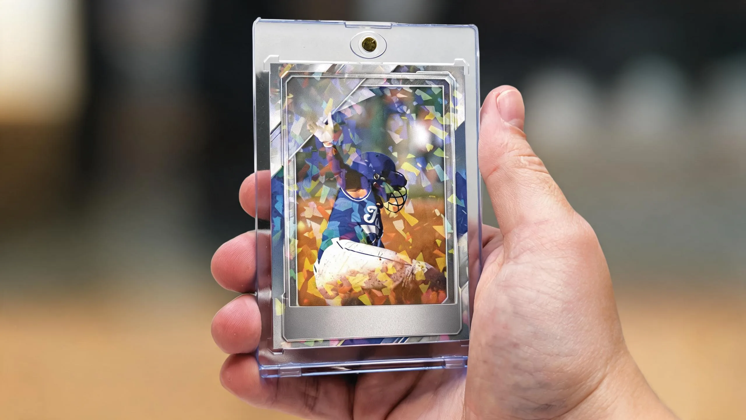 Hand holding magnetic case with blank foil-bar sports card, illustrating how to make trading cards.