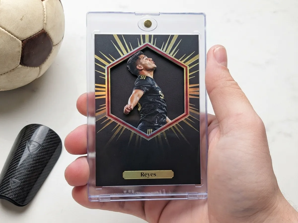 Hand holding custom soccer trading card in magnetic case, gold foil die-cut design.